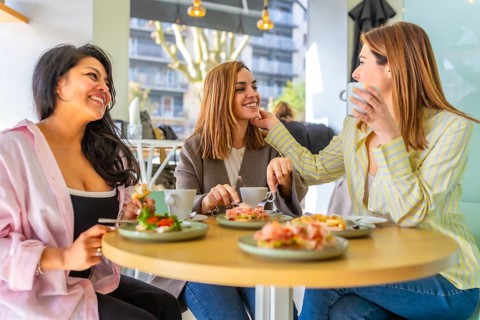 Diverse group of women spending quality time together, happily socializing, drinking coffee and