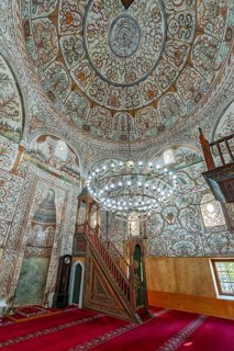 Restored interior of Et'hem Bey Mosque with detailed floral frescoes, wooden minbar and a large