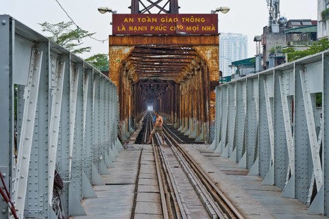 Vietnamese man walks across the tracks of the Long Bien railway bridge across the Red River, Hanoi,
