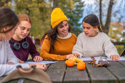 Family enjoying quality time together in a park, mother assisting her two adolescent daughters with
