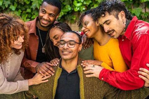 Diverse friends surrounding a man with eyes closed, sharing a moment of warm connection, comfort,