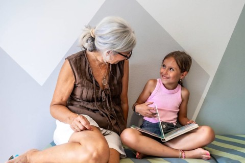 Grandmother and granddaughter are sitting close, sharing a moment of connection while reading a