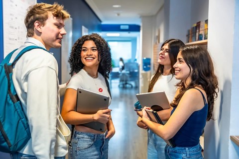 Group of multiethnic young university students standing and cheerfully talking in a modern campus