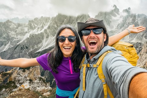 Cheerful happy couple of hikers friends taking selfie on Cadini di Misurina viewpoint. Millennial
