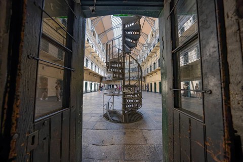 View through opened doors of a central spiral staircase in an old prison with industrial design,
