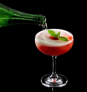 Red cocktail on a black background, filled with soda, mint as garnish, studio recording