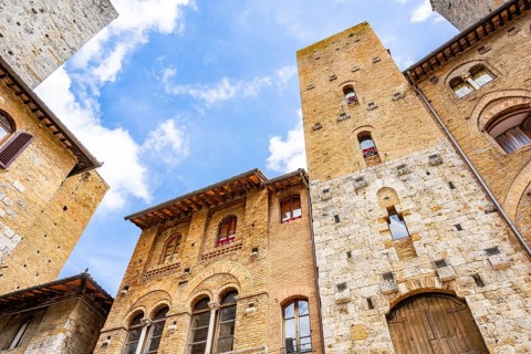 Towers of the old Town with historic buildings from Piazza del Duomo at San Gimignano on a sunny