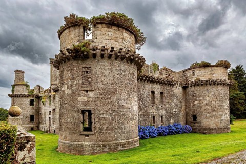 Stone castle ruins with round towers and overgrown plants under cloudy sky, The ruins of Château de