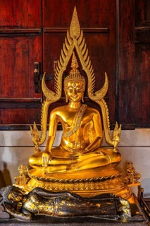 Gilded seated Buddha statue in a public prayer hall in the Wat Phra Singh Buddhist temple complex,