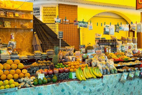 Colourful market stand with a variety of fresh fruit and products under bright lights, Central