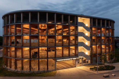03.05.2026: Illuminated modern timber parking garage (Parkhaus am Bahnhof) with a curved wooden