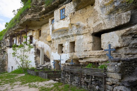 Old monastery entrance carved in rock, with crosses and a stone staircase, rock caves, cave