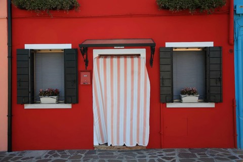 House entrance with stripe curtain and window with flowers, charming red façade, Red House on