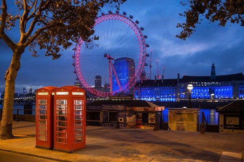 Red K6 style telephone boxes with the London Eye illuminated at dusk, South Bank, London, United