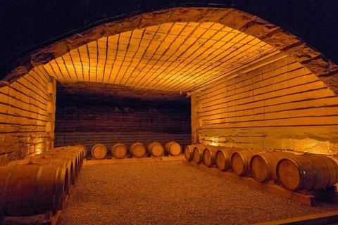 Cosy wine cellar with barrels in a warmly lit, rustic setting made of stone and wood, wine cellar,