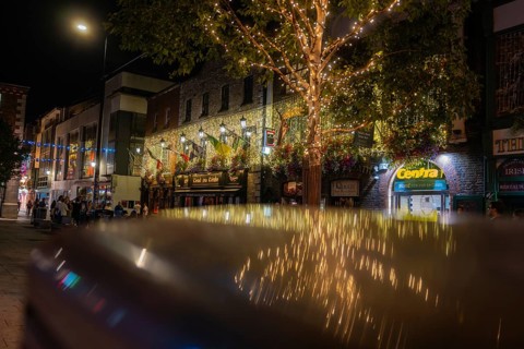 Charming, illuminated street with decorative lights and relaxed people, nightlife, Dublin, Ireland