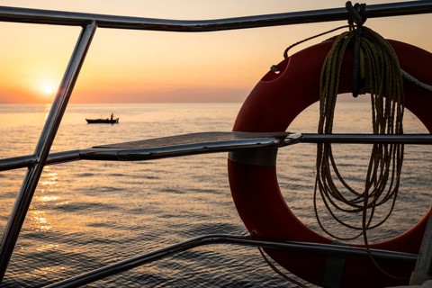 View from a sailing ship through lifebuoy of Mediterranean Sea, fishermen and fishing boat in front