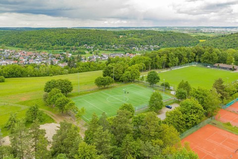 Aerial view of a sports complex with sports fields, including a soccer field and tennis courts,