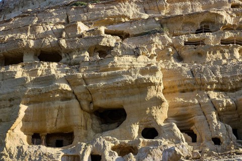 Neolithic caves, former hippie paradise, detail of eroded rock wall with small cave entrances and