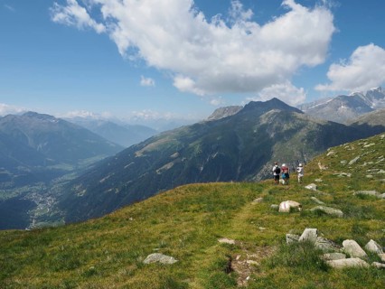 A group of hikers on the mountainside with a wide view of the surrounding peaks and valleys,