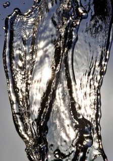 Water frozen by short exposure moving in backlight in front of the sun