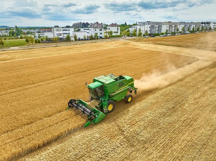 Aireal photo of a combine harvester harvesting wheat on a field in the vertile and fruitful of