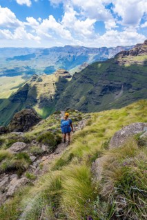Female mountaineer hiking trail to Cathedral Peak or Cathedralpiek or Mponjwana, Drakensberg,