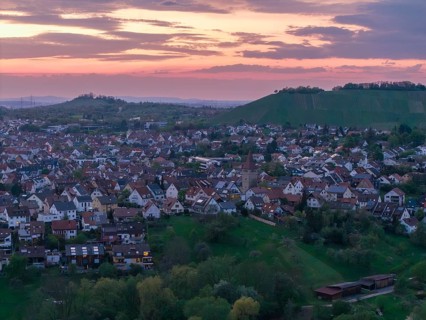 Landscape with many houses at dusk surrounded by rolling hills and a pastel-coloured sky, Korb im