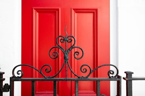 Close-up of an elegant curved metal grid in the foreground and red door in the background, Chelsea,