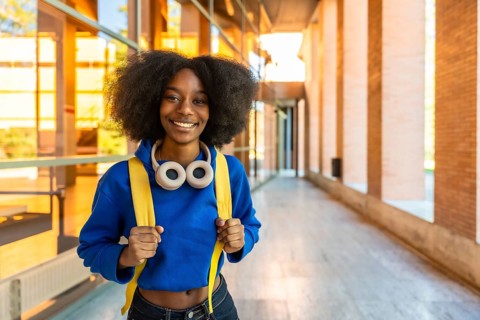 Young black woman with an afro hairstyle, wearing a blue hoodie, yellow backpack, and headphones