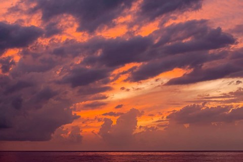 Dramatic sunset over sea with deep orange-purple clouds, Cyprus