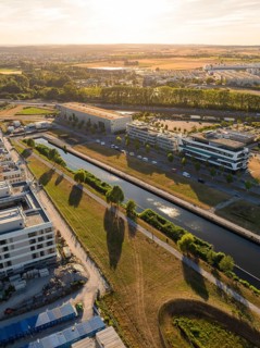 City landscape with canal and buildings at sunset, long shadows falling over green areas, airfield,