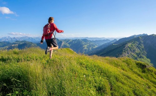 Active senior woman mountain running in warm dawn light on the ridge of the Nagelfluh chain in the