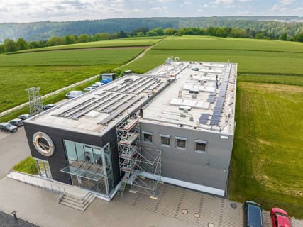 Industrial building with solar panels on the roof, surrounded by green landscapes, PV assembly,