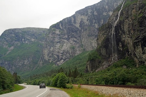 Wet road panorama with waterfall and a car driving down a narrow road, Raumadalen, Trollvegen,