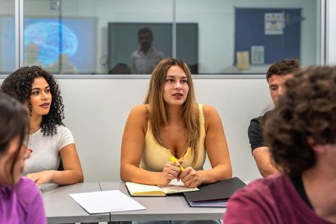 Group of diverse university students actively participating in a classroom discussion, focusing on