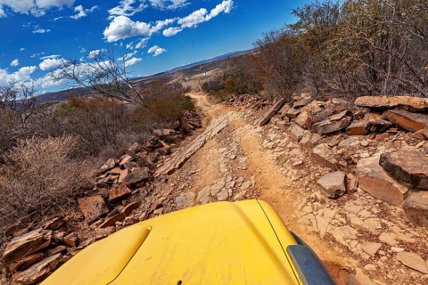 Off-road vehicle on a rocky, winding path through dry landscape, clear view into the distance, the