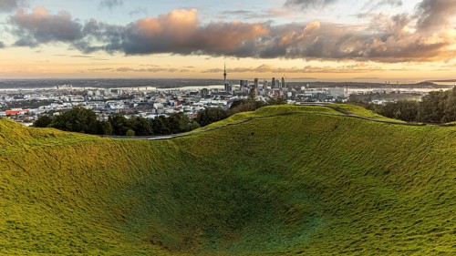 View of city behind the grass crater of the extinct volcano of Mount Eden, Auckland, New Zealand