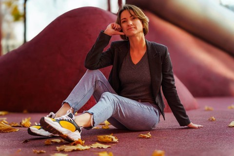 Young woman enjoying autumn leaves on red background
