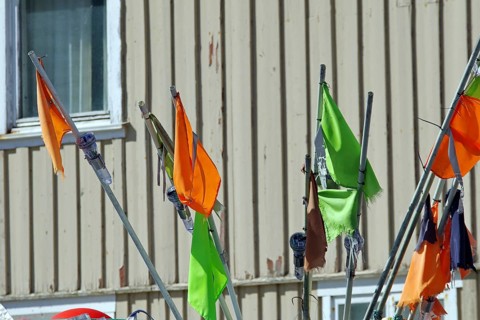 Colourful flags flutter on long poles in front of a building window, fishing, Bleik, Andøya,