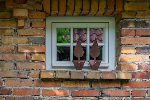 Small lattice window in a rustic brick façade, metal decoration on window ledge, North