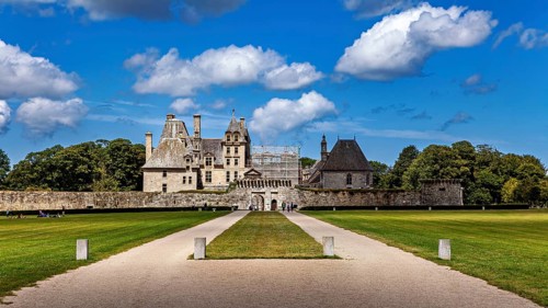A well-preserved castle with clear skies with white clouds, surrounded by lawn, Château de Kerjean