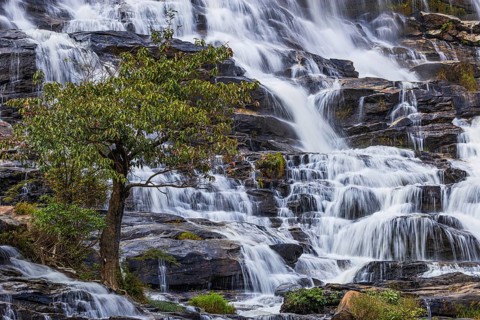 Mae Ya waterfall with cascading flowing water surrounded by lush tropical vegetation, near Doi