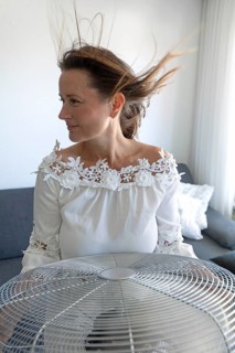 Woman with hair blowing in strong airflow from an electric fan at home. during hot weather at home