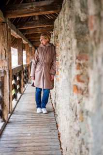 Woman leaning against a stone wall and looking around curiously in the wooden tunnel, Isny, Allgäu,