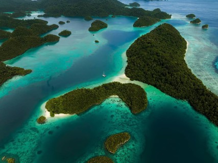 Aerial view of a sailboat surrounded by tropical islands and turquoise lagoons, Wayag Archipelagio,