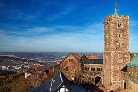 Castle with high tower and surrounding landscape under a wide blue sky, The Wartburg near Eisenach
