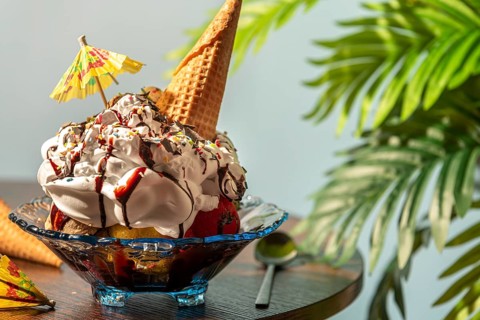Ice cream with cream, chocolate, crumble, ice cream cone and small umbrella