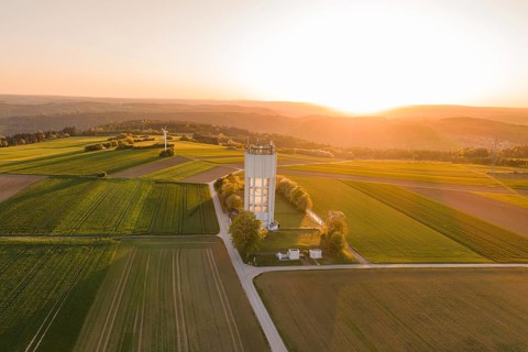 Fields with a water tower and a wind turbine, illuminated by sunset evening light, quiet