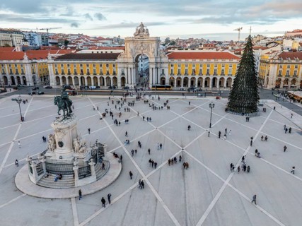 Drone view of Praca do Comercio in Lisbon, winter sunset highlights a stunning Christmas tree and